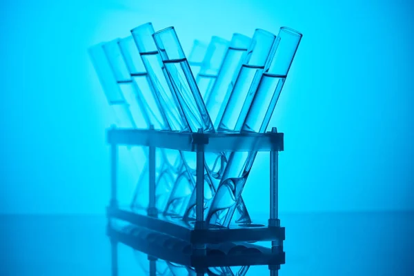 Tubes en verre avec liquide sur pied pour essai chimique sur bleu — Photo de stock