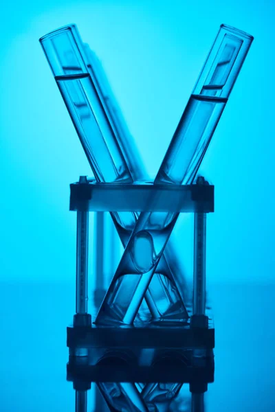 Rows of glass tubes with liquid on stand on blue — Stock Photo