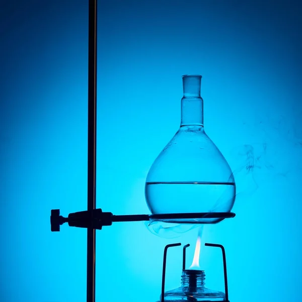 Calentamiento de líquido para ensayo químico aislado en azul - foto de stock
