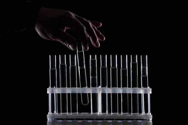 Cropped image of female chemist taking glass tube from stand isolated on black — Stock Photo