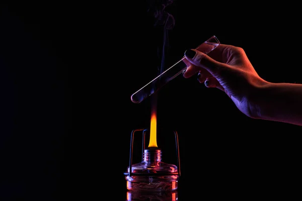 Imagen recortada de químico calentando tubo con líquido en negro - foto de stock