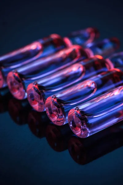 Close up of row of transparent glass ampoules with liquid on table — Stock Photo