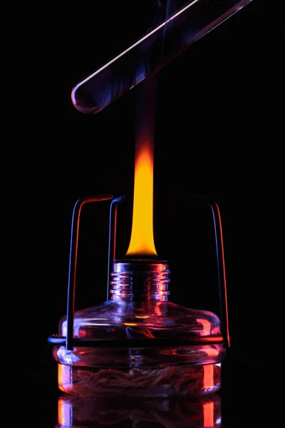 Heating tube with liquid in laboratory on black — Stock Photo