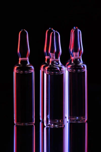 Transparent glass ampoules with light reflection on table on black — Stock Photo
