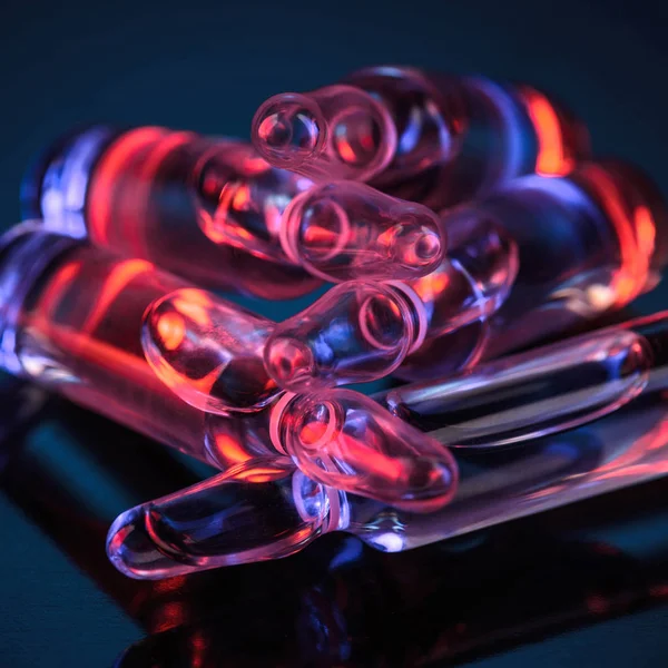 Gros plan des ampoules en verre transparent avec réflexion de la lumière rouge sur la table — Photo de stock