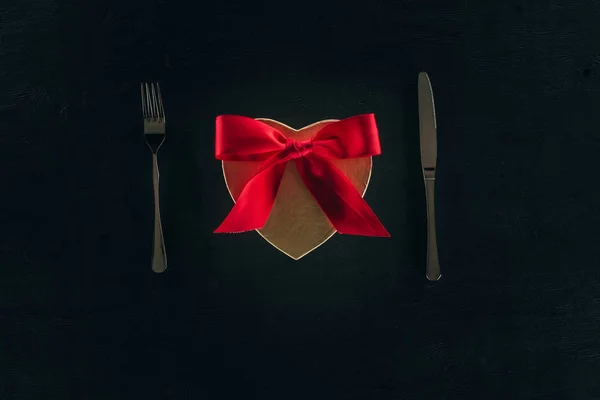 Top view of gift box in shape of heart with cutlery isolated on black — Stock Photo