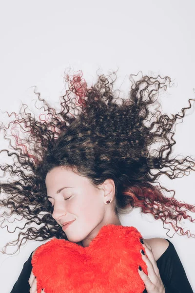 Красивая молодая женщина с подушкой в форме сердца изолированы на белом — стоковое фото