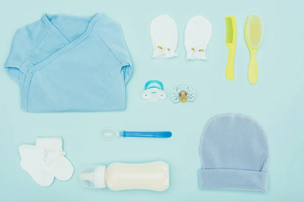 Vue de dessus des vêtements et équipements pour bébés isolés sur bleu — Photo de stock
