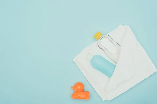 Vue de dessus des accessoires de salle de bain en serviette et canard en caoutchouc isolé sur bleu — Photo de stock