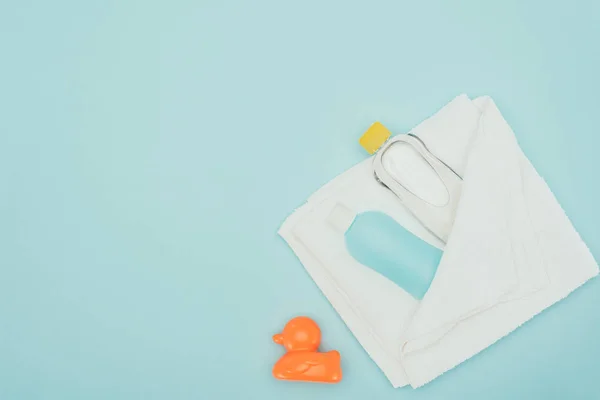 Vue de dessus des accessoires de salle de bain en serviette et canard en caoutchouc isolé sur bleu — Photo de stock