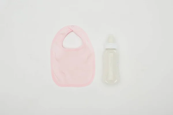 Top view of baby bib and bottle of milk isolated on white — Stock Photo