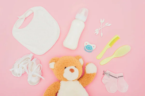 Vista superior de ursinho de pelúcia e equipamento de bebê isolado em rosa — Fotografia de Stock