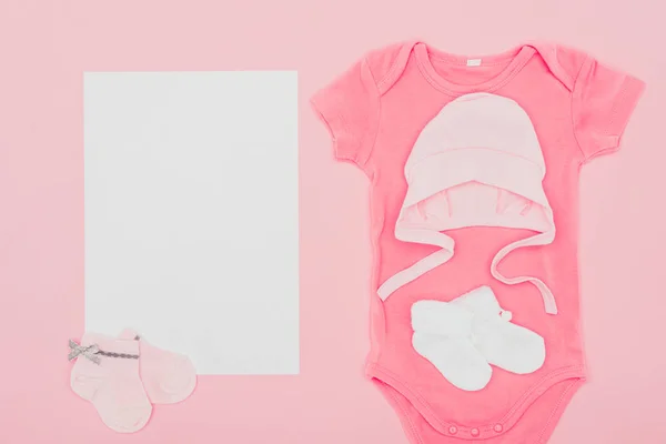 Top view of empty board with baby clothes isolated on pink — Stock Photo