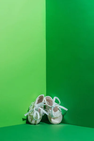 White baby shoes in corner on green — Stock Photo