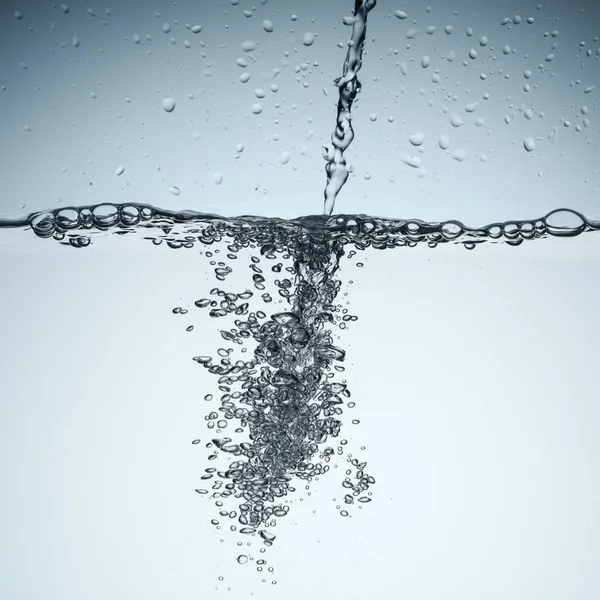 Fondo con agua que vierte con burbujas, aislado en blanco - foto de stock