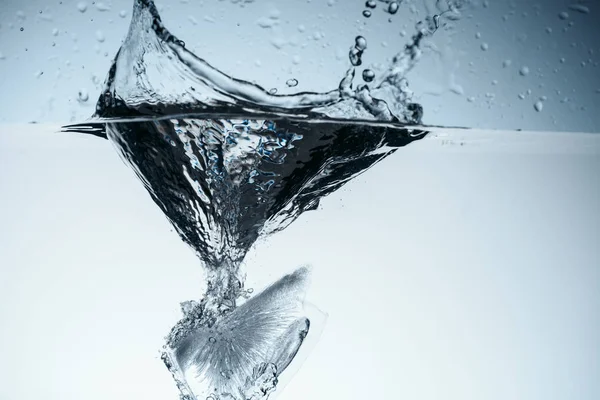 Cubo de hielo en agua con salpicadura, aislado en blanco - foto de stock