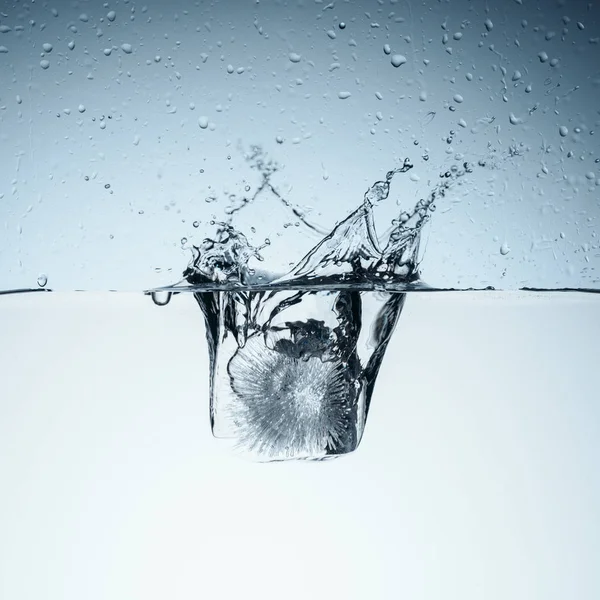 Cubo de hielo en agua con salpicaduras y gotas, aislado en blanco - foto de stock