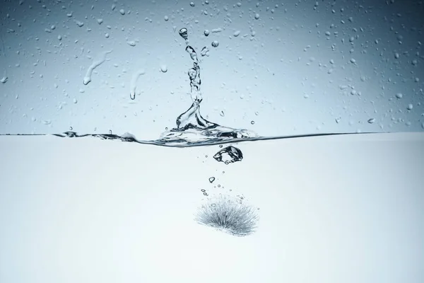 Ice cube in water with drops, isolated on white — Stock Photo