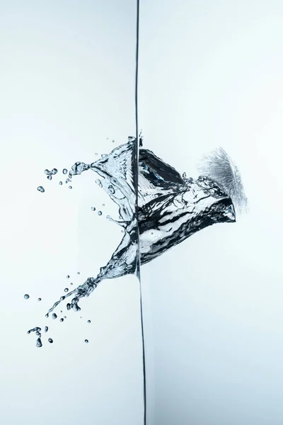 Cubo de hielo en agua pura con salpicaduras y gotas, aislado en blanco - foto de stock
