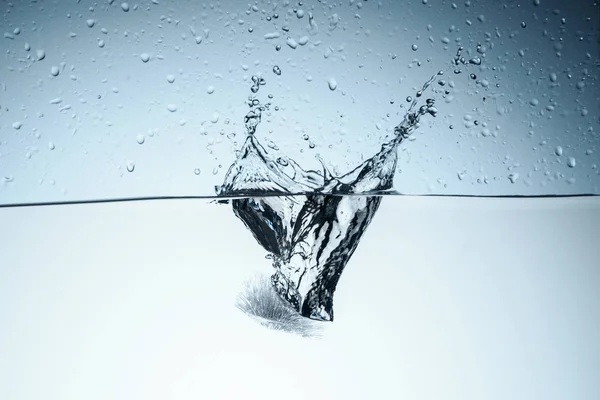 Cubo de hielo salpicando en agua con gotas, aislado en blanco - foto de stock