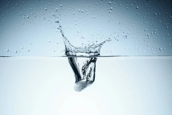 Cubo de gelo em água com respingo, isolado sobre branco — Fotografia de Stock