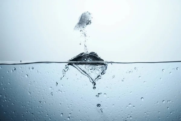 Cubo de hielo en agua pura con salpicadura, aislado en blanco - foto de stock