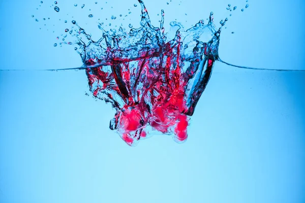 Кубики льоду з ягодами у воді з краплями, ізольовані на синьому — стокове фото