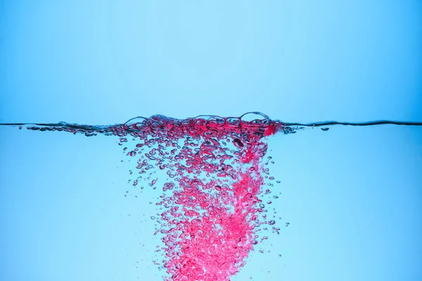 Bolhas cor-de-rosa na água, isolado em azul — Fotografia de Stock