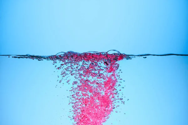 Burbujas rosadas en el agua, aisladas en azul - foto de stock