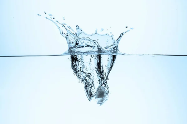 Cubo de hielo en agua con salpicaduras y gotas, aislado en blanco - foto de stock