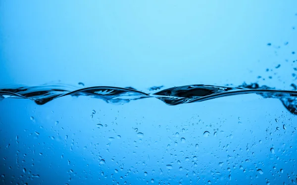 Fließende Wassertextur mit Tropfen, isoliert auf Blau — Stockfoto