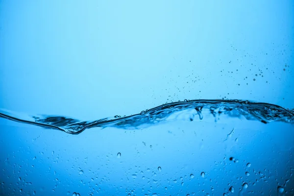 Flowing water background with drops, isolated on blue — Stock Photo