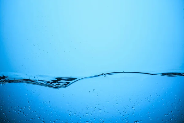 Fondo de agua que fluye con gotas, aislado en azul - foto de stock