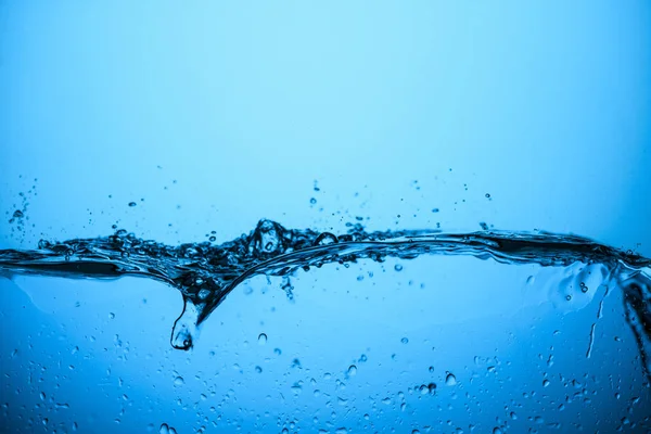 Salpicaduras de agua con burbujas, aislado en azul - foto de stock