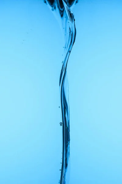 Versando acqua limpida, isolata sul blu — Foto stock