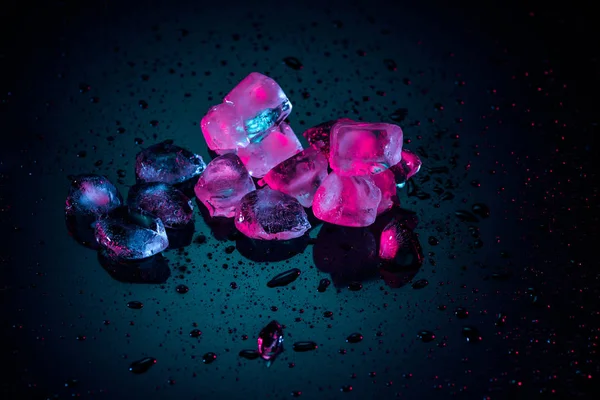 Close up de cubos de gelo rosa derretendo em preto com gotas — Fotografia de Stock