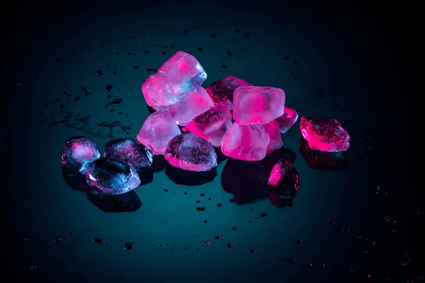 Close up of pink melting ice cubes on black with drops — Stock Photo
