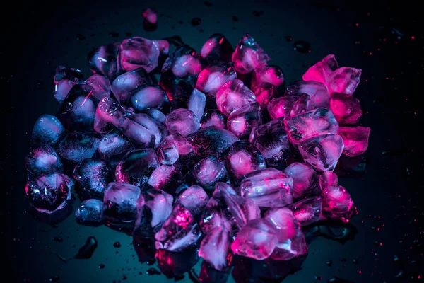 Gros plan de glaçons roses fondus sur noir — Photo de stock