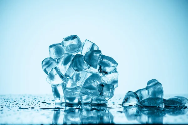 Таяние кубиков льда на белом с каплями — стоковое фото
