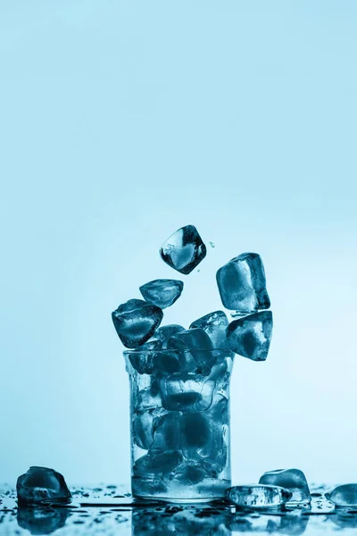 Fusion de glaçons tombant dans le verre, sur blanc avec des gouttes — Photo de stock