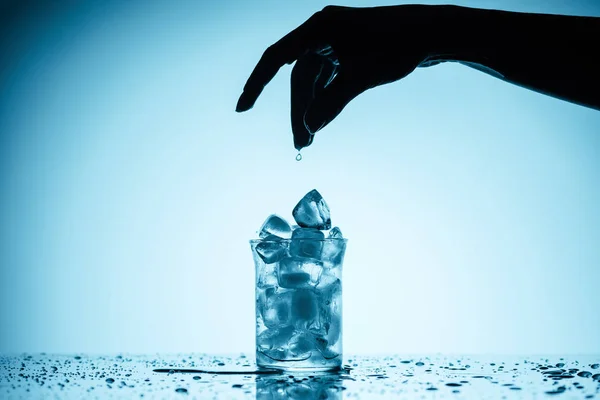 Ausgeschnittene Ansicht einer Person, die Eiswürfel ins Glas wirft — Stockfoto