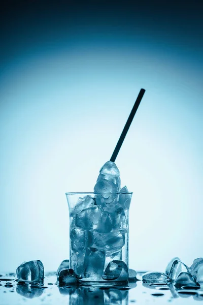 Derretendo cubos de gelo em vidro com palha, sobre branco — Fotografia de Stock