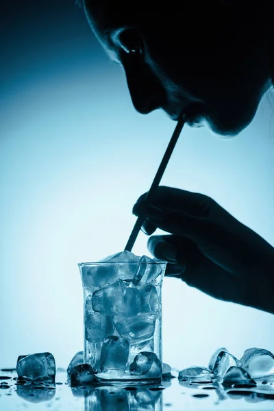 Silhueta de perfil de mulher bebendo água fria com cubos de gelo com palha — Fotografia de Stock