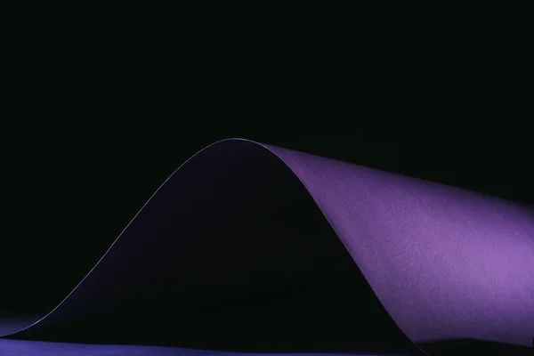 Gauchissement simple papier violet sur noir — Photo de stock
