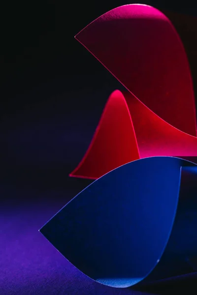 Red, blue and pink warping paper on dark surface — Stock Photo