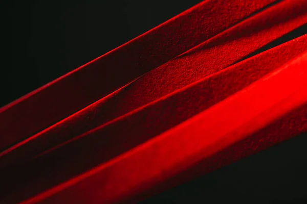 Vue rapprochée du papier rayé rouge piquant sur noir — Photo de stock