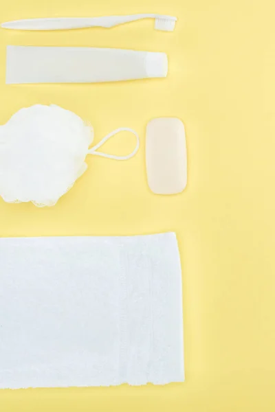 Вид зверху зубна щітка, зубна паста, рушник, мочалка і мило, ізольовані на жовтому — стокове фото