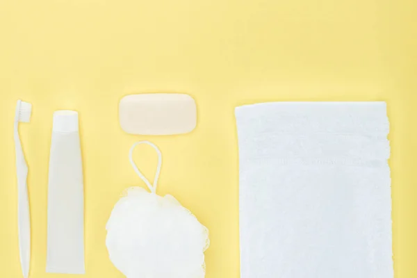 Vista superior del cepillo de dientes blanco, pasta de dientes, toalla, paño y jabón, aislado en amarillo - foto de stock