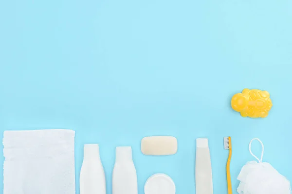 Vista superior de brinquedo, escova de dentes, pasta de dentes, toalha e sabão, isolado em azul — Fotografia de Stock