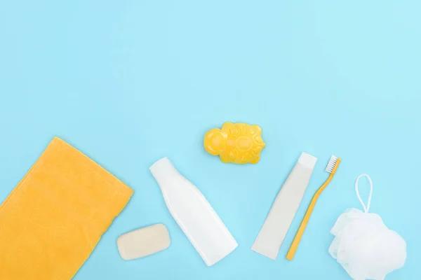 Top view of body lotion, toothbrush, toothpaste, towel and soap, isolated on blue — Stock Photo